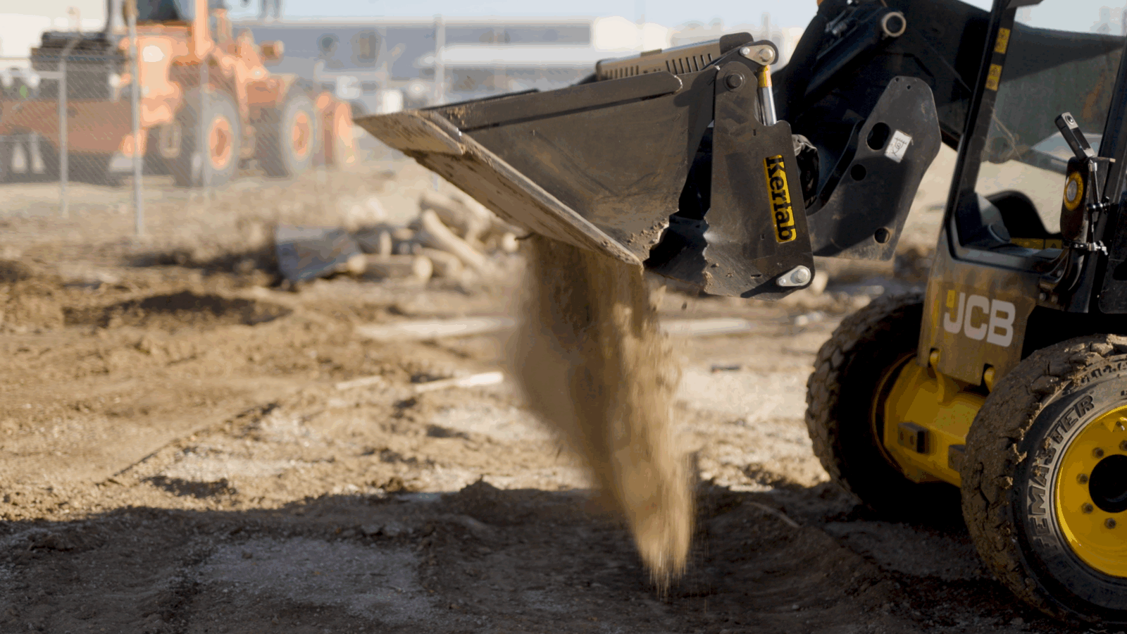 4 in 1 dumping materials Kerfab skid steer 4-in-1 bucket dumping soil on a worksite.