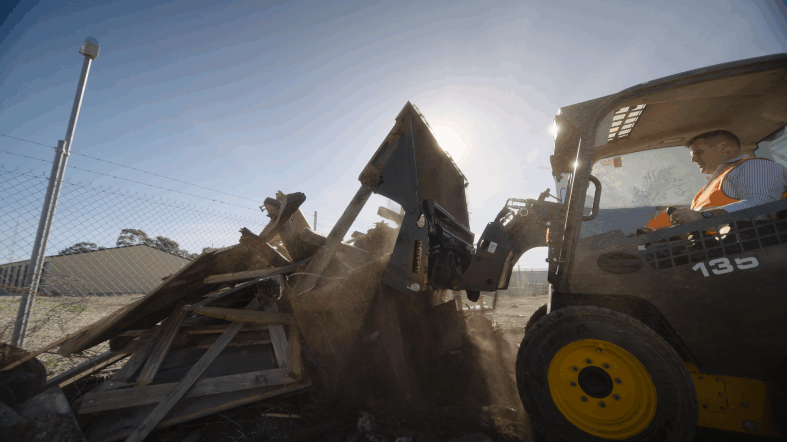 skid steer 4 in 1 dumping Kerfab skid steer 4-in-1 bucket dumping soil on a worksite.