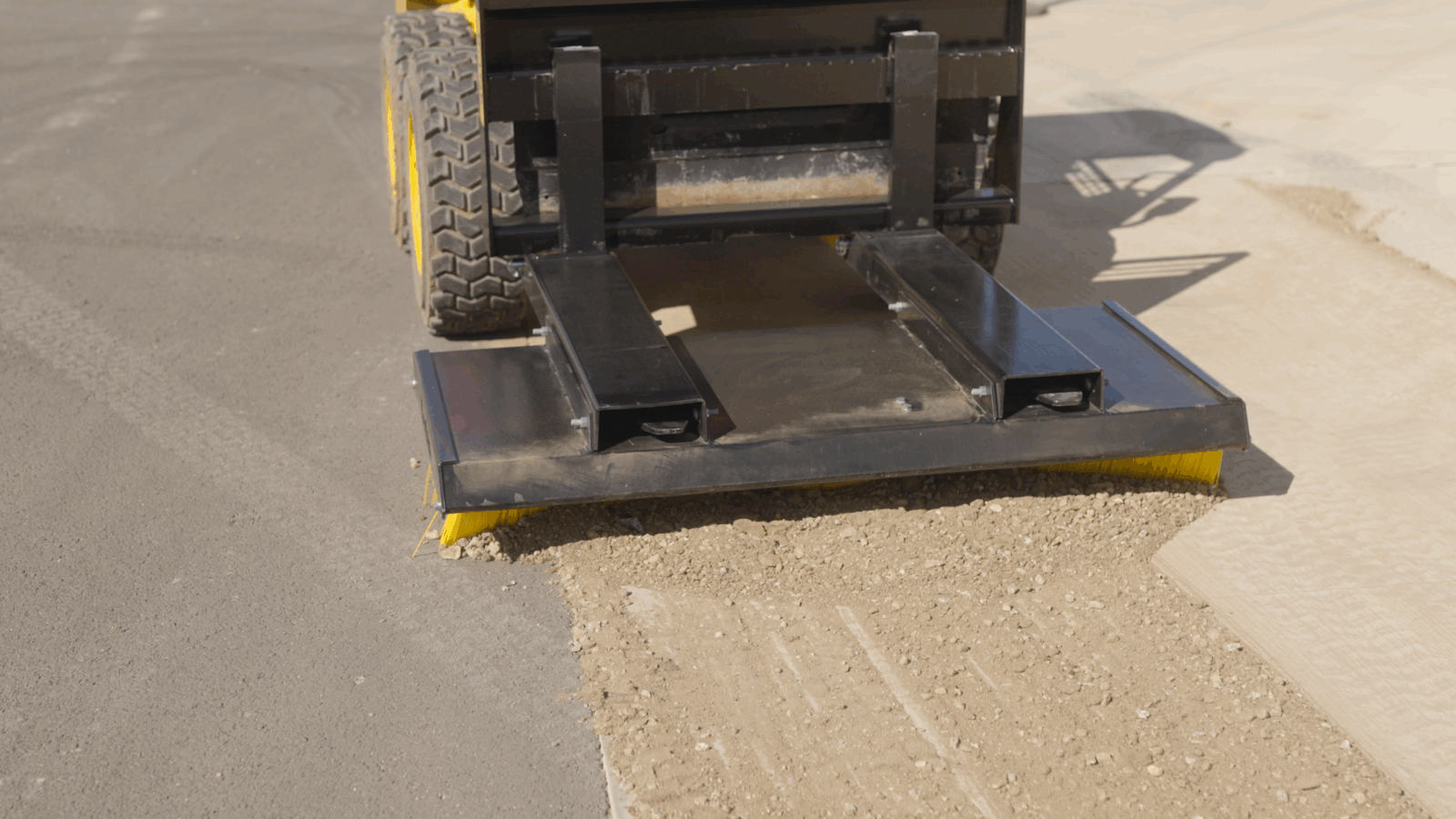 10 Kerfab K-Broom push broom on a skid steer sweeping loose gravel from pavement during site clean-up.